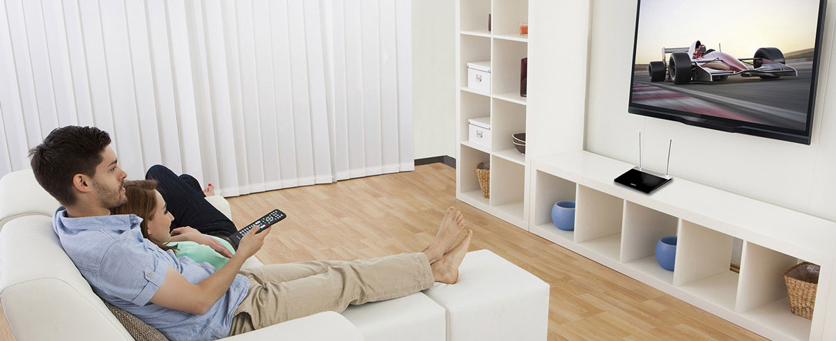 Un hombre y una mujer sentados en un sofá, viendo la televisión