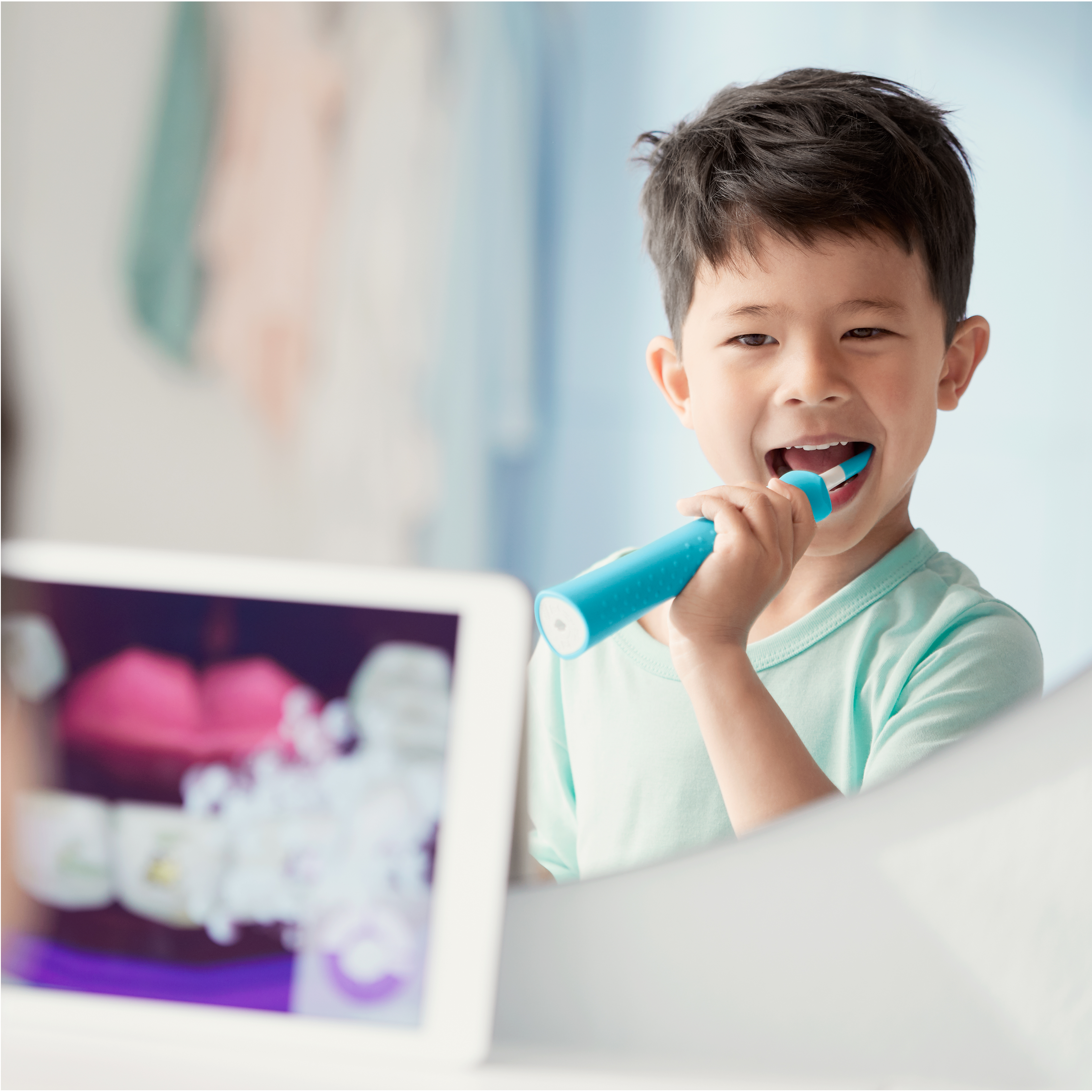 Un niño usando un cepillo dental eléctrico Sonicare for Kids mientras mira la aplicación Sonicare for Kids